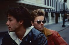 two young men sitting next to each other on the sidewalk