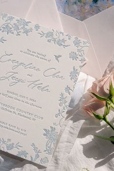 the wedding stationery is laid out on top of each other, with flowers in between them