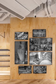 several framed photographs hang on the wall in an empty room with wooden slats and metal railings