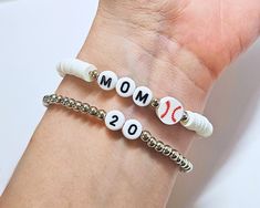 Baseball Mom Clay Bead Bracelet | Personalizable Heishi Baseball Mom Stretch Bracelet | Stackable Bracelets Gift for Her IMPORTANT NOTE: This listing is for a single bracelet or up to 2 bracelets depending on option selection. Details: Handmade Item Bracelet Length: See Size Chart in Images Materials: 4mm silver or gold plated beads (tarnish resistant), plastic letter beads, baseball charm bead Closure: Tie Made to Order Personalization: Bead Colors: See color chart in images Accent Bead Colors: Gold plated, silver plated, or rose gold plated  "mom" phrasing: indicate in personalization box for variations such as "mama." If no specification in personalization box, MOM will be used as default. ✨ Please measure your wrist before ordering as we do not offer returns or exchanges for resizing. Baseball Bracelet Diy, Mom Clay Bead Bracelet, Baseball Mom Bracelet, Bracelet Business, Baseball Bracelet, Single Bracelet, Clay Bead Bracelet, Plastic Letters, Diy Jewlery