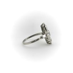 a white gold ring with diamonds on the sides and an oval design in the middle