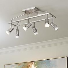 an overhead track light fixture in a living room with paintings on the wall behind it