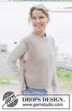 a woman standing in front of a lake with her hands on her hips and smiling at the camera