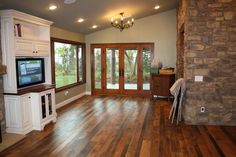 an empty living room with wood floors and large windows