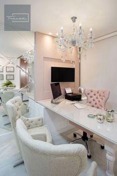 a white desk with chairs and a laptop on top of it next to a chandelier