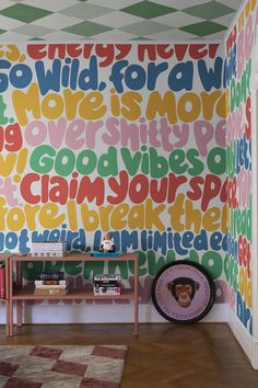 a colorful wallpapered room with a wooden table in front of it and a checkered rug on the floor