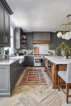 a kitchen with gray cabinets and white counter tops, an area rug on the floor