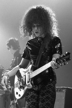 a woman with long hair playing an electric guitar