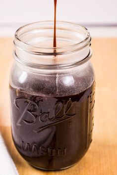 a glass jar filled with liquid sitting on top of a wooden table