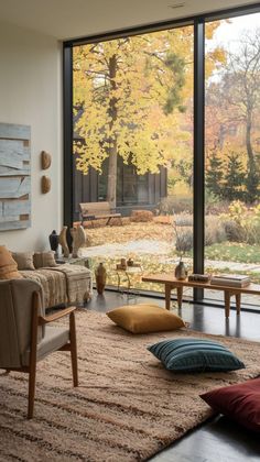 a living room filled with lots of furniture and large glass doors that look out onto the woods