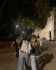 three people walking down the street at night