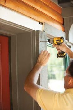 a man is using a drill to fix a window