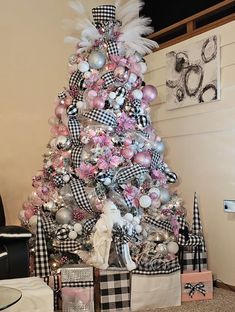 a pink and black christmas tree decorated with white, silver, and pink ornaments is shown