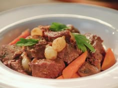 a white bowl filled with meat and carrots