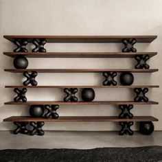 a wooden shelf filled with black vases on top of it's sides in front of a white wall