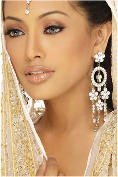 a woman in a white dress with gold jewelry on her head and veil over her face