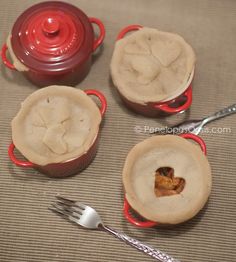 four small pies are sitting on the table next to a fork and cupcake tin