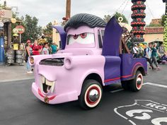 a purple truck with an evil face on it's side in a parade at disney world