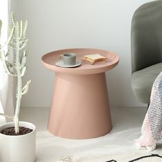 a small table with a cup on it next to a potted plant