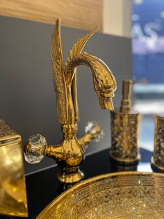 a gold faucet and soap dispenser sitting on top of a black counter