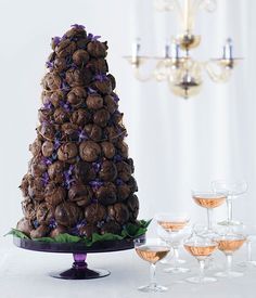 a table topped with wine glasses and a pine cone centerpiece on top of a cake stand