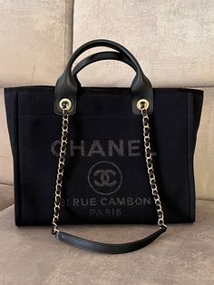 Chanel Deauville Tote medium new size with microchip and removable internal clochette. New arrival in our collection! New item. Total black cotton with champagne hardware and neutral linen colour inside. Full set boutique: box, dustbag, microchip, brochure, glove, camelia, ribbon, black shopping bag with storage invoice. We insert the picture to help you understand the difference between the regular large size and a new medium size Year 07/2022 Measurements: 34 x 27 x 17 cm Medium Excellent as a Chanel Large Bag, Chanel Canvas Bag, Tote Bag Chanel, Champagne Hardware, Tote Chanel, Chanel Shopping Bag, Black Shopping Bag, Chanel Canvas, Chanel Tote Bag