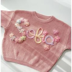 a pink sweater with the word hope written on it and colorful flowers in the middle