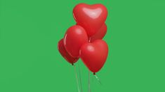 three red heart shaped balloons floating in the air on a green screen with space for text