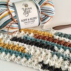 a ball of yarn sitting on top of a crocheted blanket next to a pair of scissors