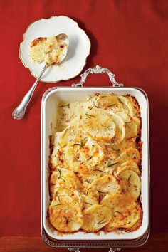 a casserole dish with potatoes and gravy on a red tablecloth