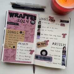 an open notebook with various stickers on it and a candle next to it,