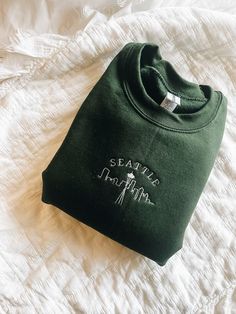 The cozy accessory your closet has been missing 🏙 This is a made to order item. Please allow 1-2 weeks before item is shipped. Embroidered crewneck sweatshirt. 50% preshrunk cotton, 50 % polyester. Unisex fit. Design size is approximately 2x4 inches Grey Embroidered Sweatshirt, Relaxed Fit Crew Sweater With Embroidered Logo, Green Casual Hoodie With Custom Embroidery, Casual Green Hoodie With Custom Embroidery, Crew Neck Sweatshirt With Embroidered Logo, Cotton Crew Neck Sweatshirt With Embroidered Graphics, Green Cotton Crew Sweatshirt, Green Sweater With Embroidered Logo For Fall, Fall Green Sweater With Embroidered Logo