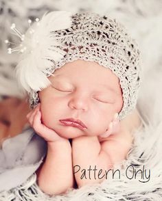 a newborn baby wearing a white crochet hat with feathers on it's head