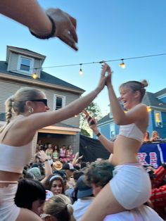 two women in white bikinis are dancing at an outdoor event