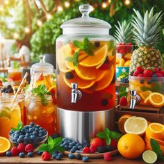 a pitcher filled with liquid surrounded by various fruits and drinks on a table in front of some pineapples