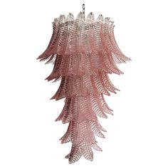 a pink glass chandelier hanging from a ceiling fixture with leaves on the bottom