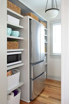 a stainless steel refrigerator freezer sitting inside of a kitchen next to a wooden floor