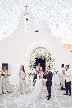 a bride and groom standing in front of a church with confetti falling from the sky