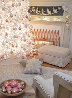 a decorated christmas tree in the corner of a living room with white and pink ornaments