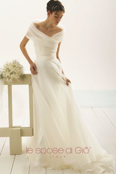 a woman in a wedding dress standing next to a chair