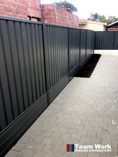 a brick walkway leading to a black fence