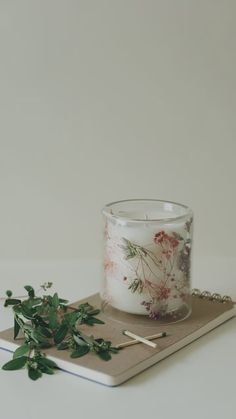 a glass candle sitting on top of a tray next to a green leafy plant