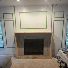 a living room that has been painted white with green lines on the wall and fireplace