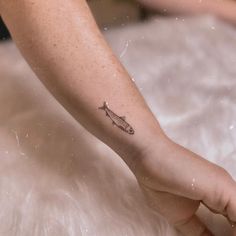 a small fish tattoo on the left wrist