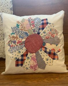 a white pillow with an embroidered flower on the front and back of it, sitting on a wooden floor