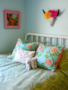 there is a stuffed animal on the bed with two pillows in front of it and a cow skull mounted to the wall