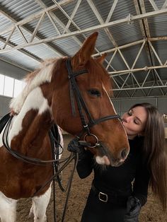 a woman standing next to a brown and white horse