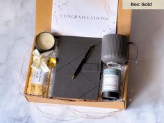 an open box containing candles, pens, and other personal care items on a marble surface