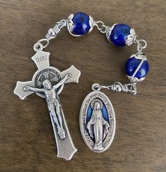 "This beautiful Chaplet is made of 10mm blue tone beads, stainless steel wire, 1\" miraculous medal and 2 inches crucifix." Blue Rosary With 8mm Beads And Crucifix, Blue Rosary With 8mm Beads In Cross Shape, Adjustable Rosary With Miraculous Medal And Crucifix, Blue Cross Jewelry With 8mm Beads, Blue Cross-shaped Jewelry With 8mm Beads, Adjustable Blue Rosary With Miraculous Medal, Rugged Rosary, Paracord Rosary, Blue Rosary