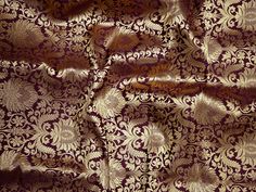 an image of a purple and gold fabric with intricate designs on it's surface